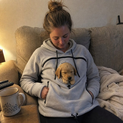 Cucciolo addormentato nella felpa marsupio grigia, sul divano di casa