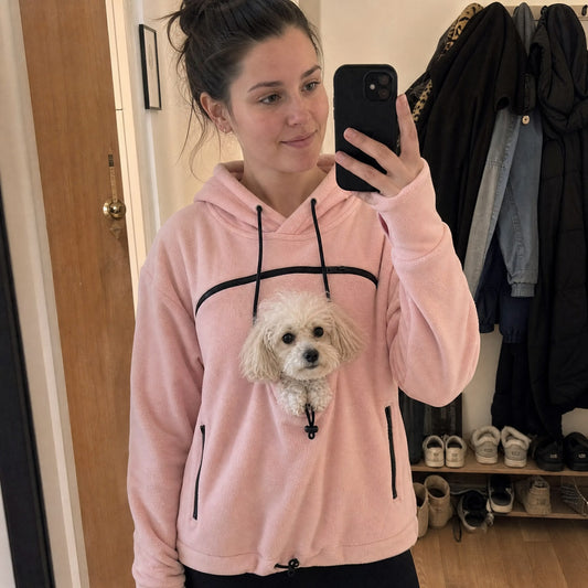 Felpa marsupio rosa indossata in casa, con un barboncino toy che spunta dal foro sul petto